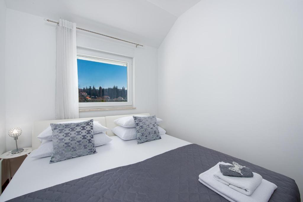 een witte slaapkamer met een groot bed en een raam bij Pelko Apartment in Dubrovnik