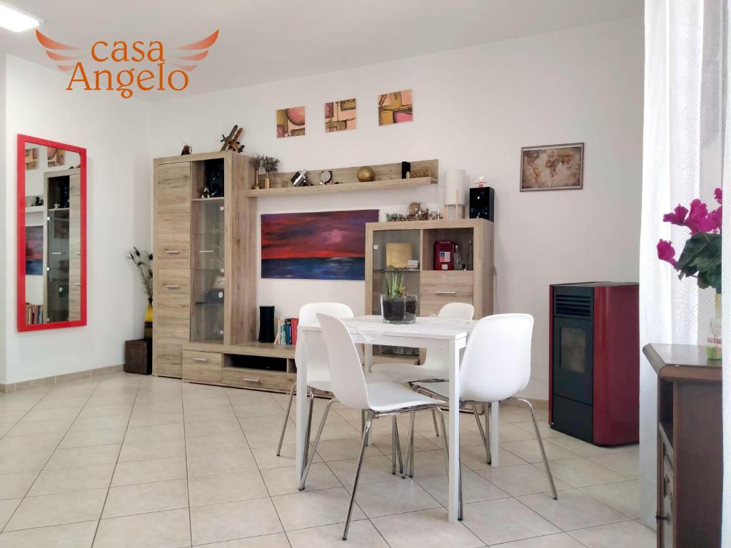 a dining room with a table and white chairs at Casa Angelo B&B in Calasetta