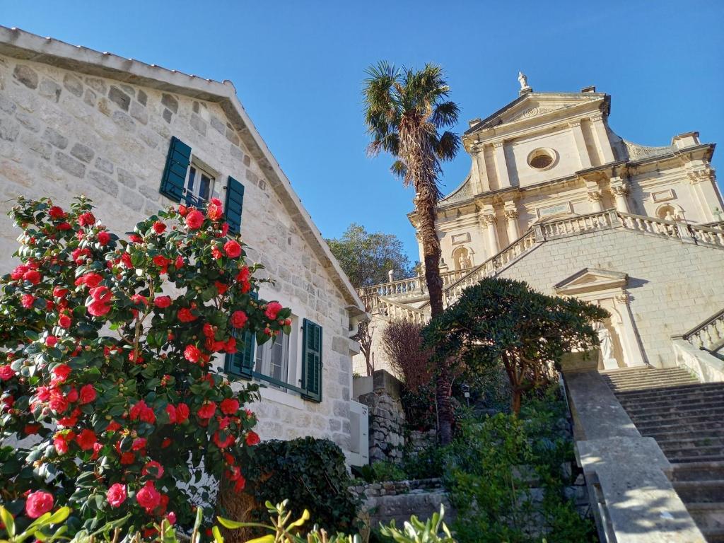 un edificio con un árbol y un edificio con rosas rojas en Romantic stone house by the sea ****, en Kotor