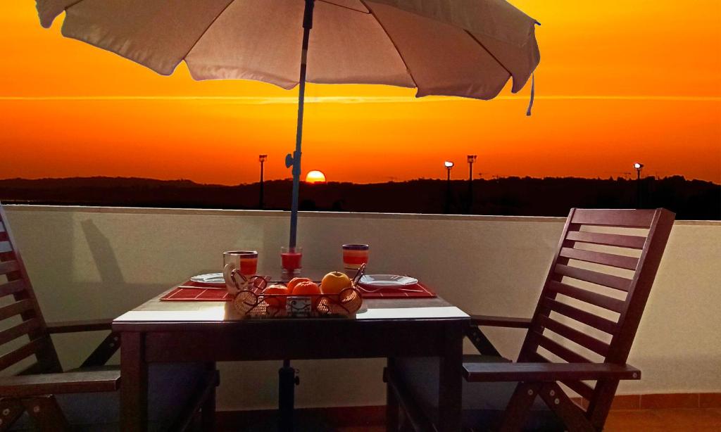 une table avec un parapluie et une assiette de nourriture dans l'établissement Studio At The Beach, à Alvor