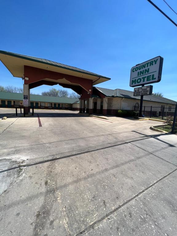 an empty parking lot with a sign in front of a motel at COUNTRY INN MOTEL in San Antonio