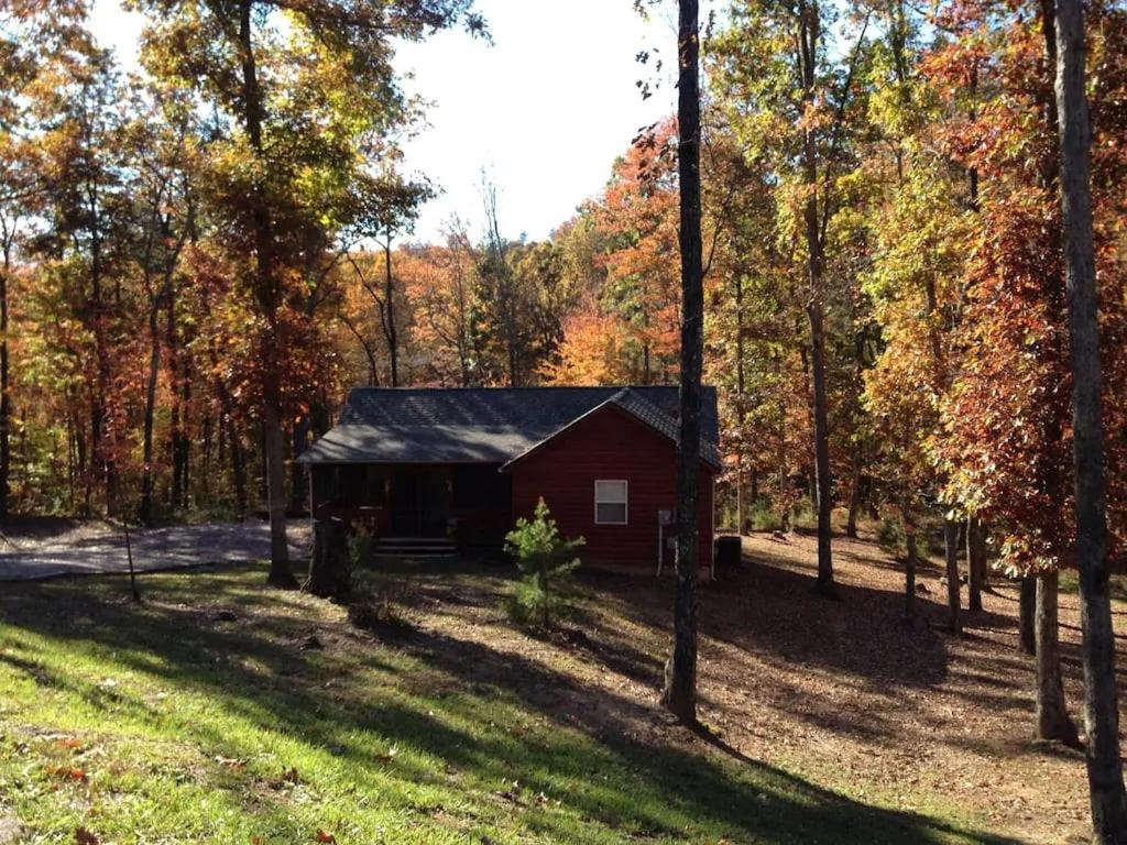 a red cabin in the middle of a forest at Gas fireplace and a great firepit with cedar adirondack chairs! in Spencer
