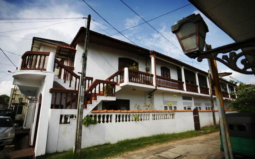 ein weißes Haus mit Holzbalkonen darauf in der Unterkunft Wijenayake's - Beach Haven Guest House - Galle Fort in Galle