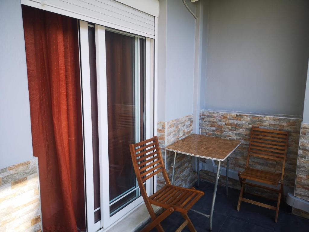 balcón con 2 sillas, mesa y ventana en ΧΑΡΗΣ ROOMS, en Kritharia