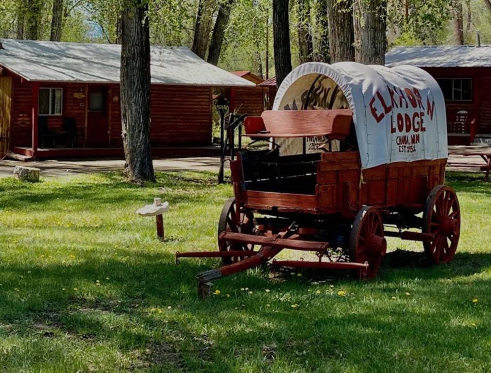 a wooden cart sitting in the grass in front of a cabin at Elkhorn Lodge in Chama