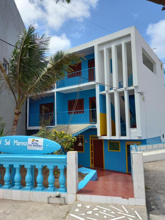una casa blu e bianca con una palma di Hotel Sol Marina a Tarrafal
