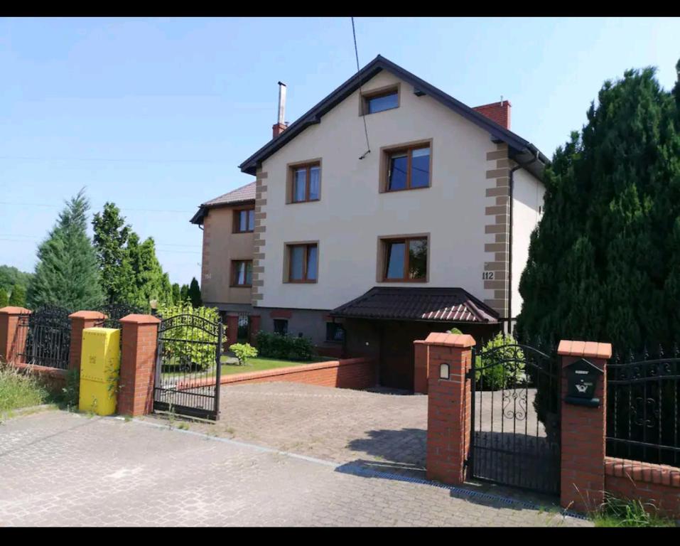 a white house with a black fence and a driveway at Apartament w domu z kominkiem i ogrodem in Reda