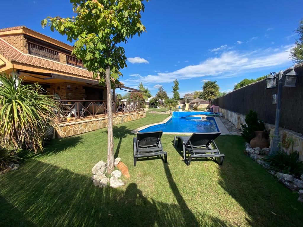 a backyard with a pool and two chairs and a tree at Casa rural Las Vegas in Pelayos de la Presa