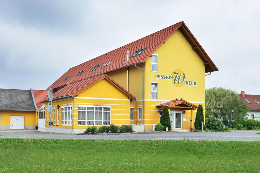 un edificio amarillo con un cartel en el costado en Frühstückspension Winter, en Gössendorf