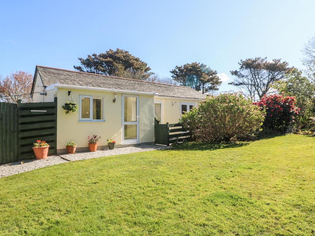 a small yellow house with a green yard at Garden Cottage in Penzance