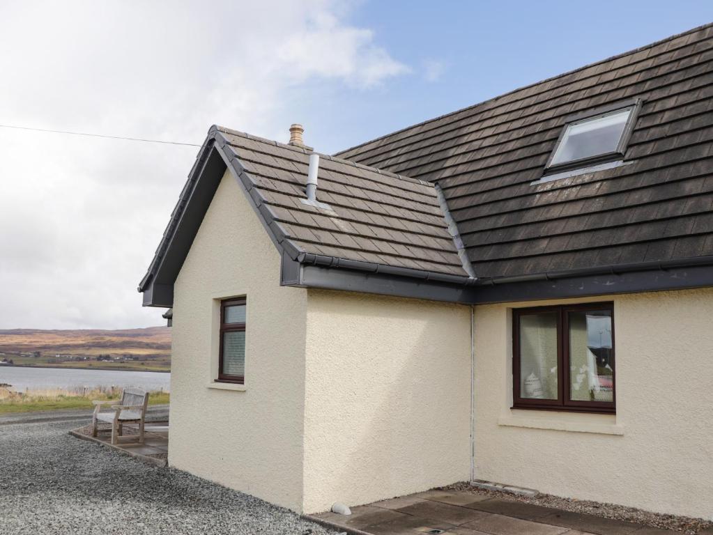 une maison blanche avec un toit noir dans l'établissement Sealladh an Locha Cottage, à Kensaleyre