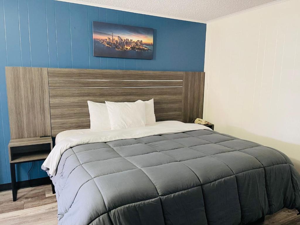 a bedroom with a large bed with a blue wall at Crown Inn Motel in Linden