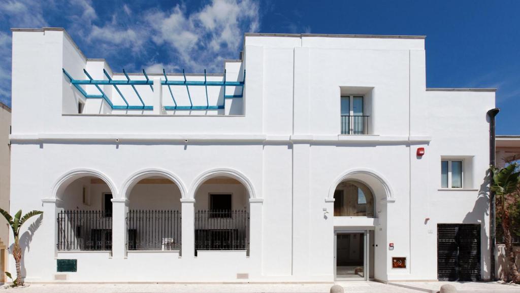 ein weißes Haus mit Seitenbögen in der Unterkunft Hyencos Hotel Callyon in Torre San Giovanni Ugento