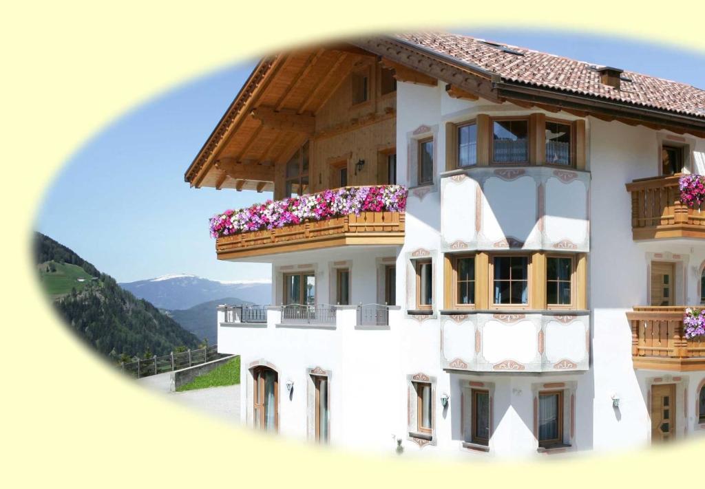 een wit gebouw met balkons en bloemen erop bij Appartamenti Hetty in Santa Cristina in Val Gardena