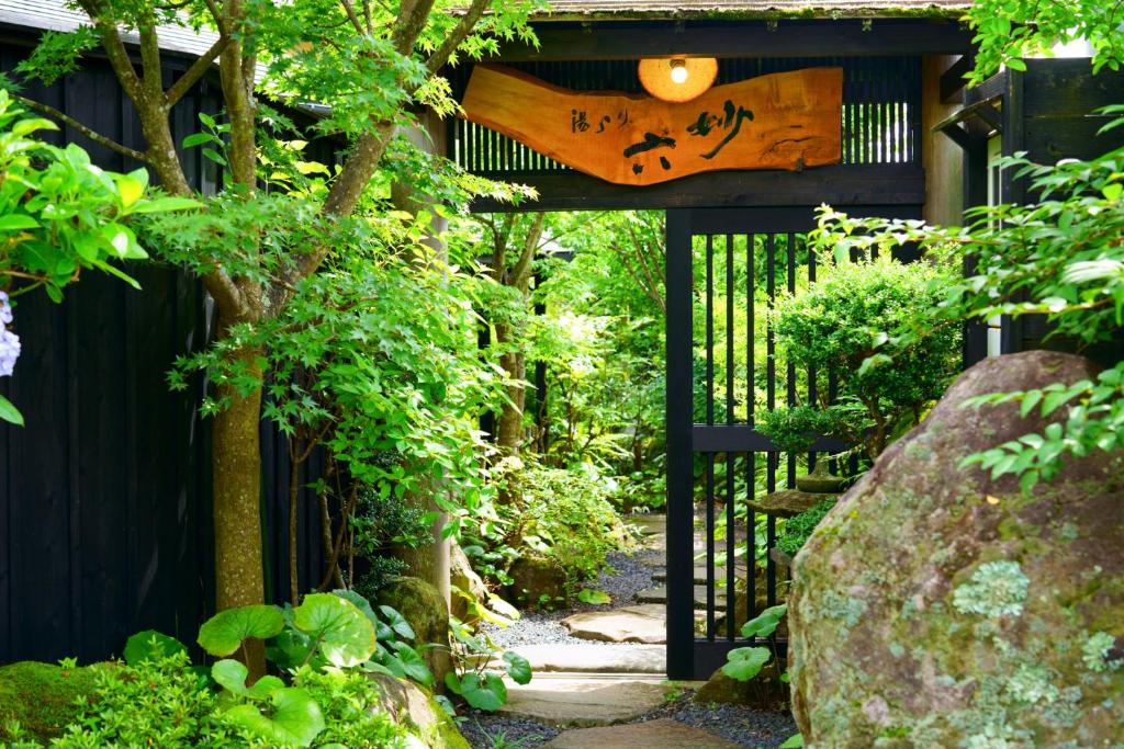 un jardin avec une porte noire et un chemin dans l'établissement Yurari Rokumyo, à Yufu