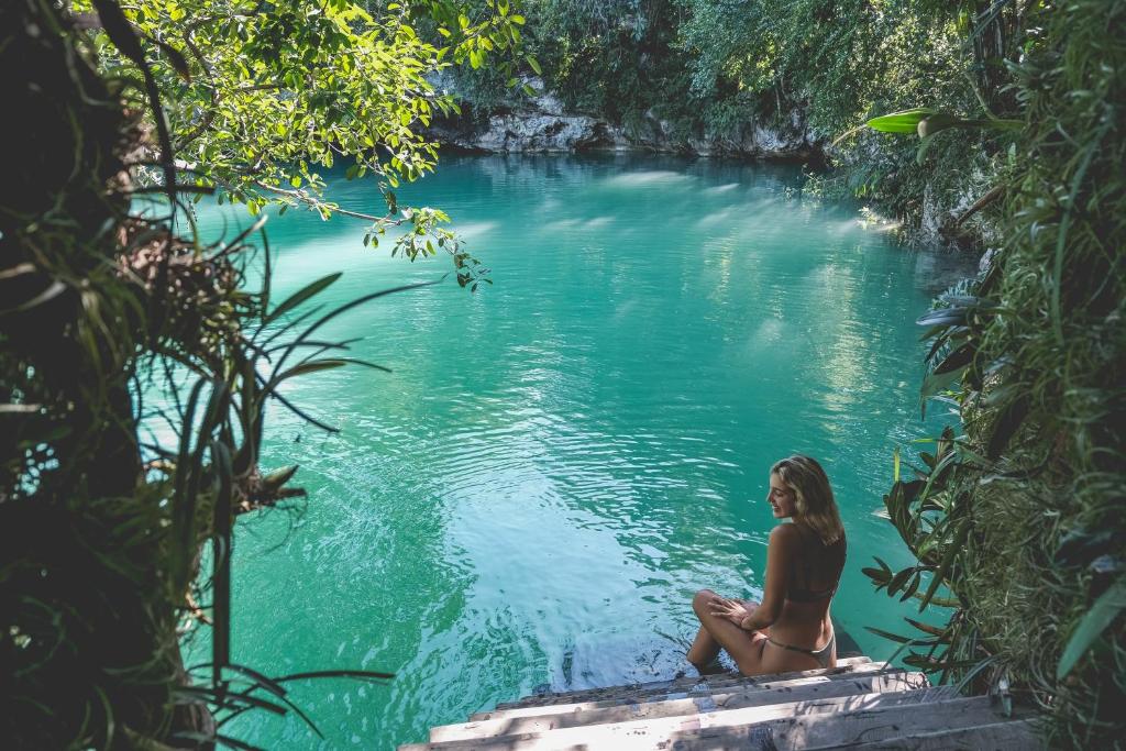 Wakax Hacienda - Cenote & Boutique Hotel في تولوم: امرأة جالسة في هيئة ماء