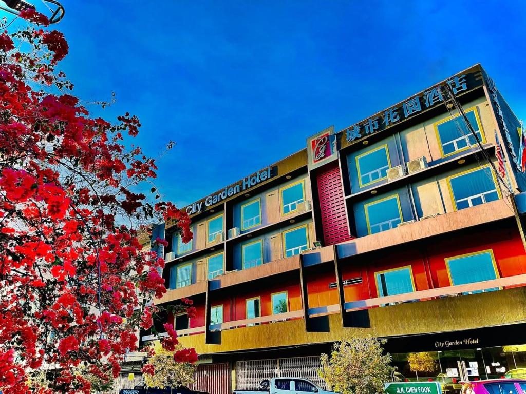 a building with colorful windows and a tree at City Garden Hotel in Tawau