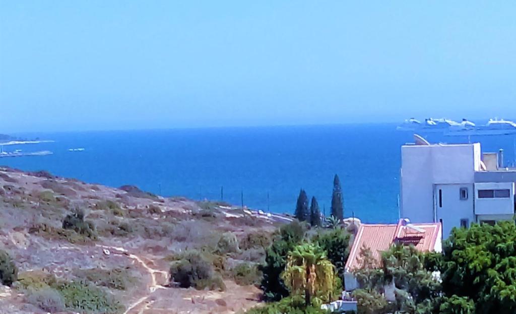 ein Haus auf einem Hügel mit dem Ozean im Hintergrund in der Unterkunft 1 bedroom apartment with a magnificent sea view in Limassol