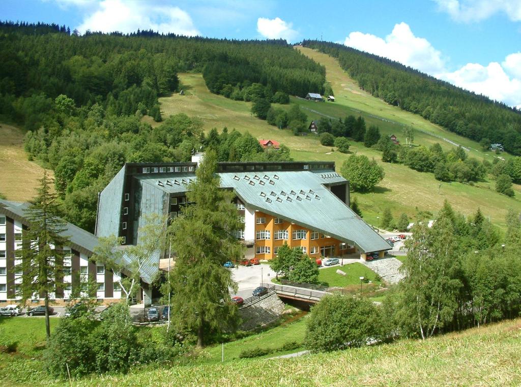 a building in the middle of a hill with trees at Hotel Fit Fun in Harrachov