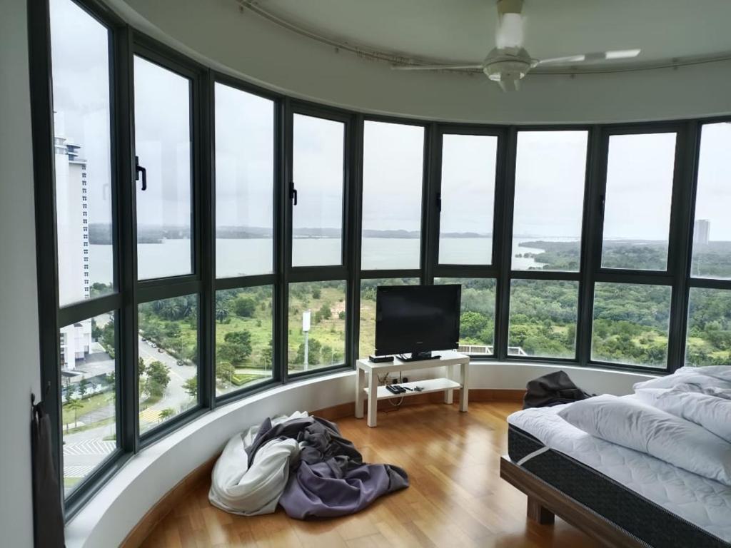 a bedroom with a bed and a tv and windows at Johor Malaysia Teega Suites@ Puteri Harbour Condo 4607 Persiaran Lasamana , Teega Suites in Nusajaya