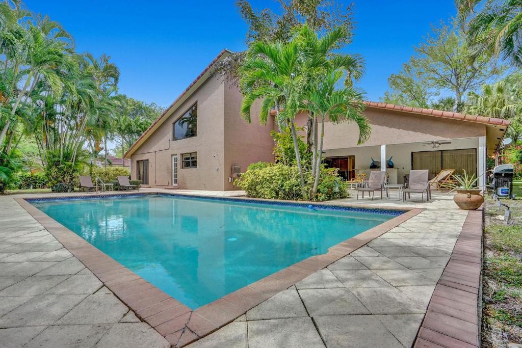 a swimming pool in front of a house with palm trees at Modern 6br Villa Resort Style Pool On Golf Course in Pompano Beach