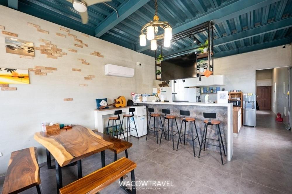a kitchen with a counter and bar with stools at Liuqiu Backpackers Hostel in Xiaoliuqiu