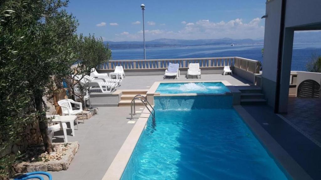 a swimming pool with chairs and a view of the water at Apartments Mlad - with pool in Rogač