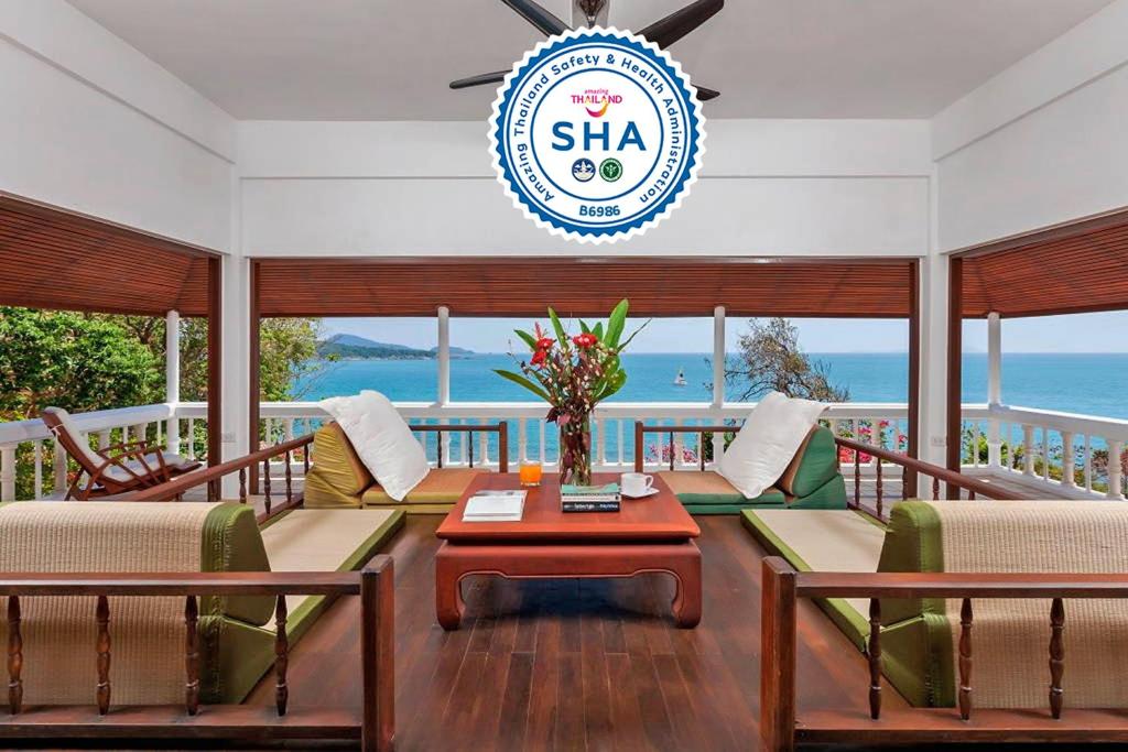 a living room with chairs and a table and a sign at Baan Khunying - Secluded Phuket Beachfront Villa - SHA Certified in Rawai Beach