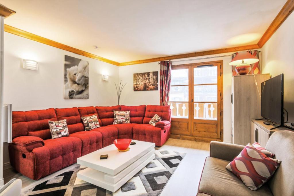 un salon avec un canapé rouge et une table dans l'établissement Résidence Les Arcs 1950 Le Village - maeva Home - Appartement 2 pièces 4 personnes Exclusive MAE-2311, à Bourg-Saint-Maurice