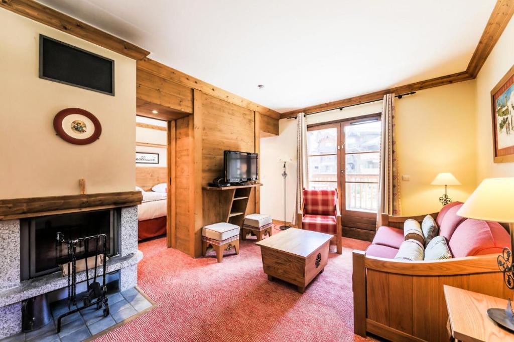 un salon avec un canapé et une cheminée dans l'établissement Résidence Les Arcs 1950 Le Village - maeva Home - Appartement 2 pièces 4 personnes Sélection MAE-4064, à Bourg-Saint-Maurice