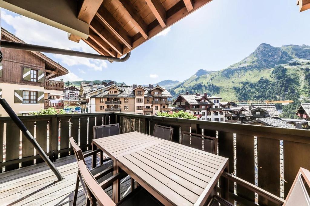 une table et des chaises en bois sur un balcon avec des montagnes dans l'établissement Résidence Les Arcs 1950 Le Village - maeva Home - Appartement 3 Pièces 6 Personnes - Sélection MAE-2357, à Bourg-Saint-Maurice