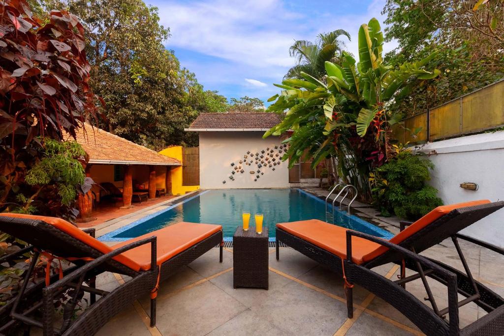 a swimming pool with two chairs and a table at StayVista at Terra Rosa - Pet Friendly Villa in Chorao