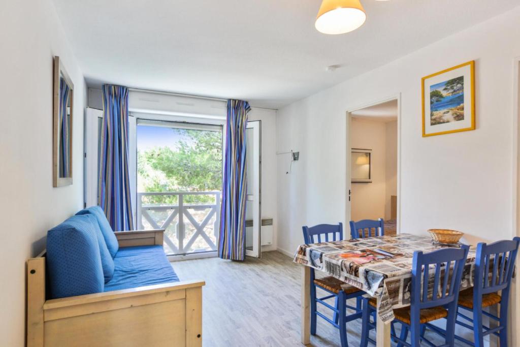 een eetkamer met een tafel en een blauwe stoel bij Résidence Debussy - maeva Home - Appartement 2 Pièces 4 Personnes - Budget 37 in Carnoux