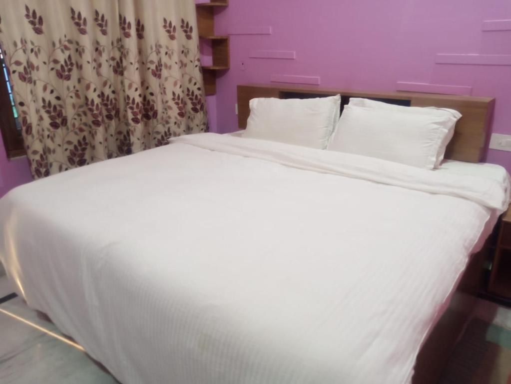 a large white bed with white sheets and pillows at CHÉRI HOME Stay in Khajurāho