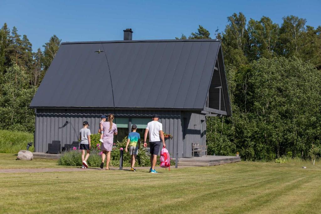 um grupo de pessoas andando em frente a um celeiro em Piesta Kuusikaru riverside cottage in Soomaa region em Kullimaa