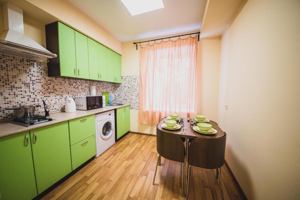 a kitchen with green cabinets and a table with dishes on it at Kvartira Klassika na Prospekte Kultury 11 in Omsk