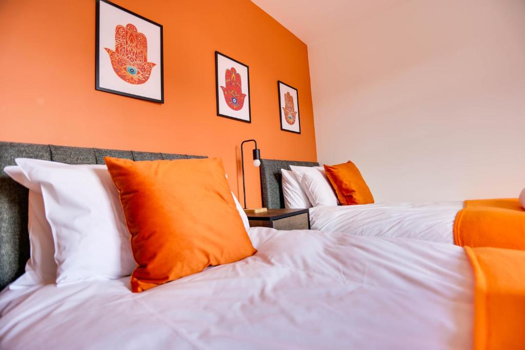 two beds in a room with orange walls at STALDON COURT - Open Plan Apartment, High Speed Wi-Fi, Free Parking in Swindon