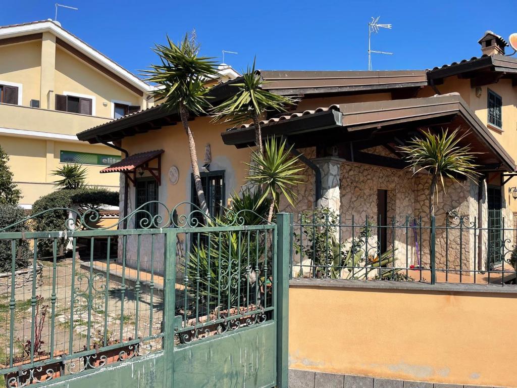 a house with a green fence and palm trees at AURA l.t in Fiumicino