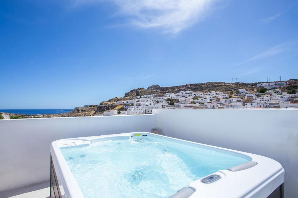 a bath tub on a balcony with a view of a city at Heritage Luxury Suites in Lindos