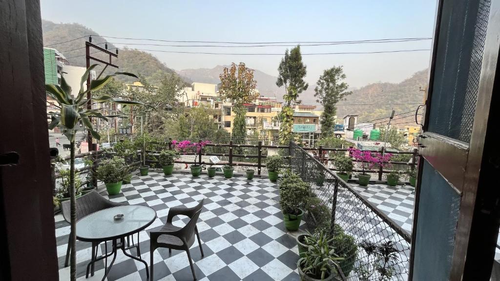 a balcony with a table and chairs on a checkered floor at Green Hills Cottage Rishikesh in Rishīkesh