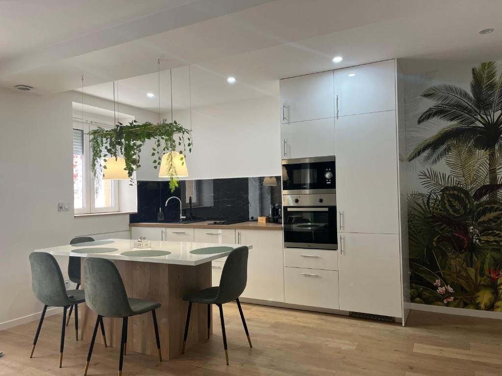 une cuisine avec des armoires blanches et une table et des chaises dans l'établissement Appartement Luxe Jaune, à Saint Etienne