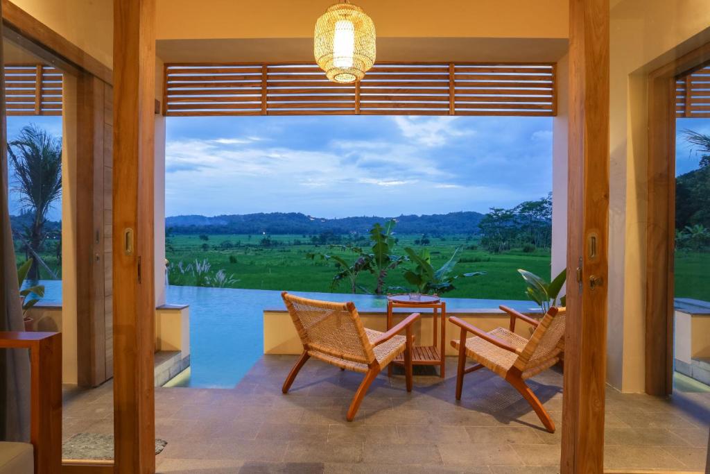 een patio met een tafel en stoelen en uitzicht op het water bij boutique villa jogja senang in Yogyakarta