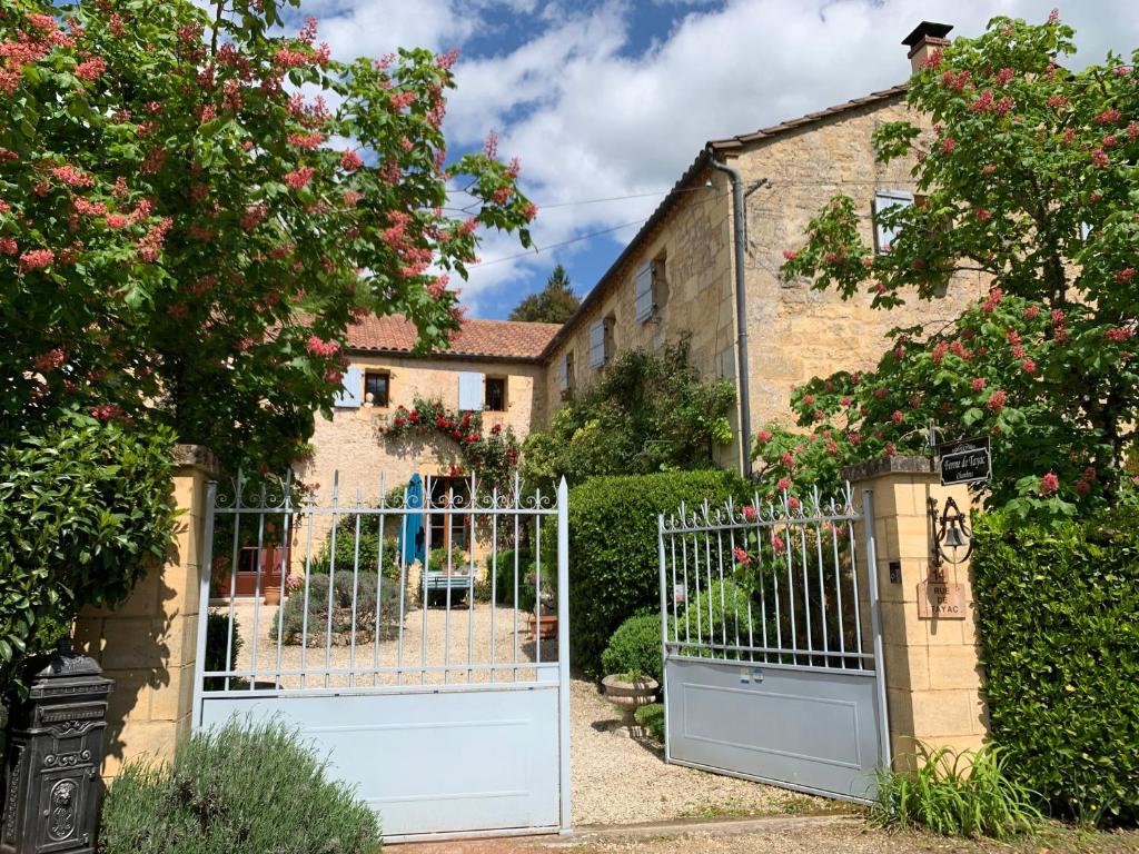 a white gate in front of a house with roses at Ferme de Tayac - Charme avec Pool in Les Eyzies-de-Tayac