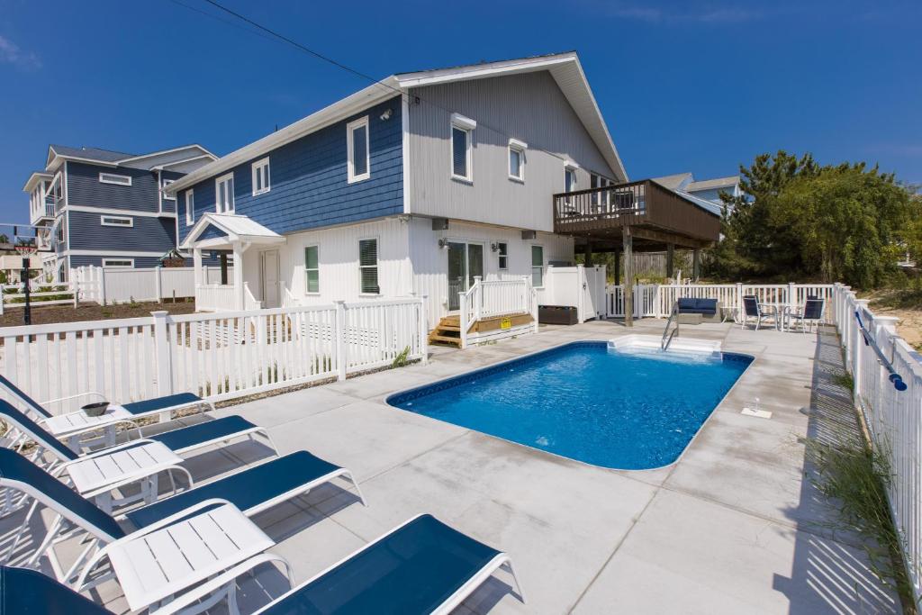 a swimming pool with lounge chairs and a house at Lazy Day-Z in Virginia Beach