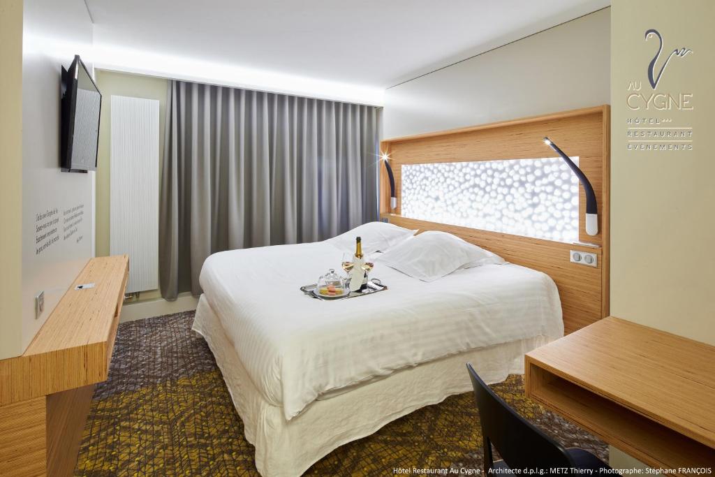 Una habitación de hotel con una cama con una bandeja de comida. en Hôtel Restaurant Au Cygne, en Eschau