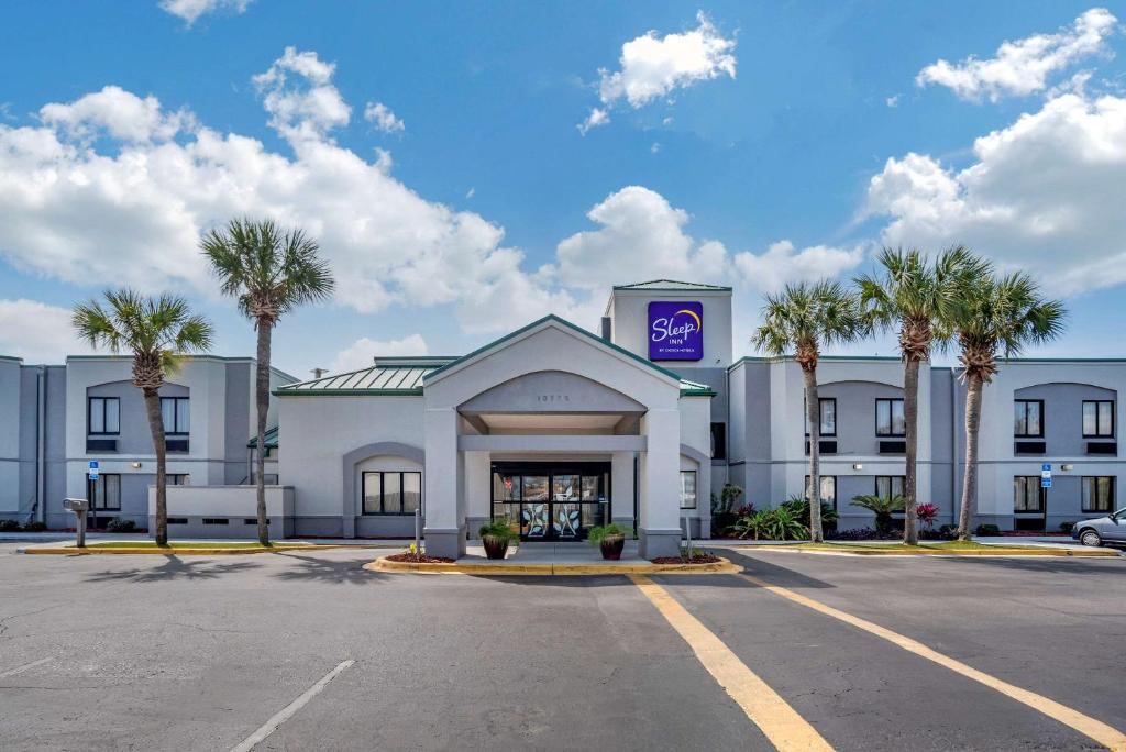 a hotel with palm trees in front of a parking lot at Sleep Inn Destin near Miramar Beach in Destin