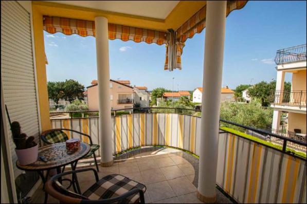 eine Veranda mit einem Tisch und Stühlen auf dem Balkon in der Unterkunft Appartement Sunny Maj in Poreč