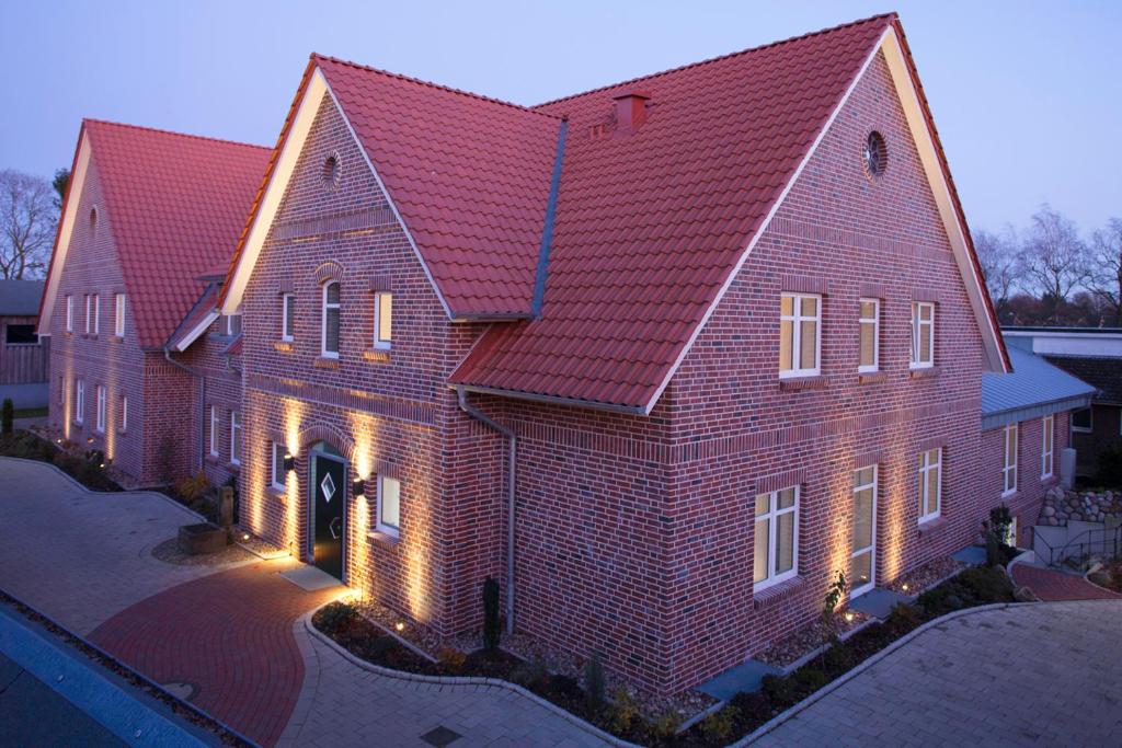 un grand bâtiment en briques avec un toit rouge dans l'établissement Hotel & Landgasthof Hoheluft, à Buchholz in der Nordheide