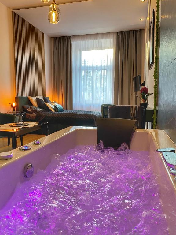 a bath tub covered in purple lights in a living room at Apartament czarny z jacuzzi in Krakow