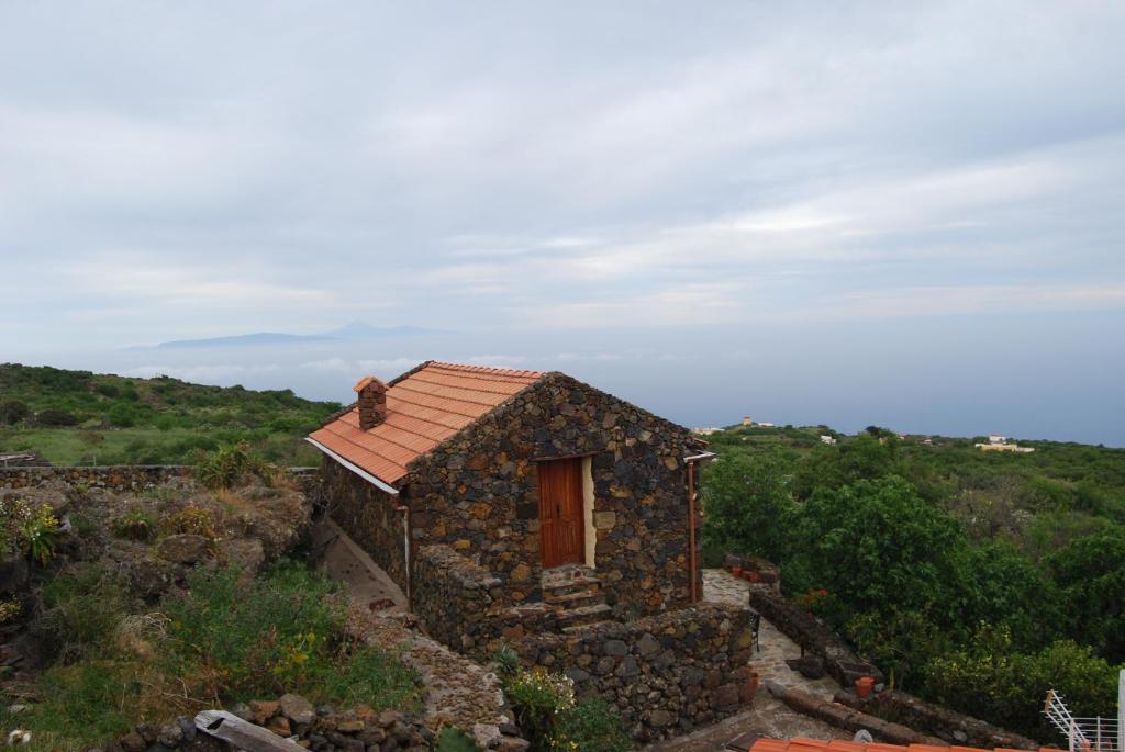 un pequeño edificio de piedra con techo rojo en Casa Abuela Estebana, en Isora